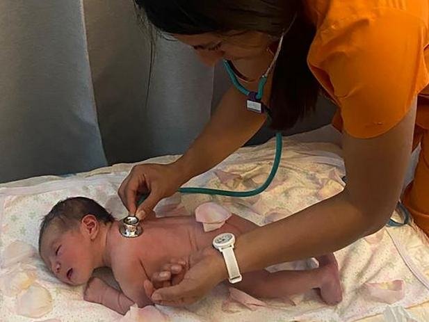 Una partera chequea la salud de un recién nacido.