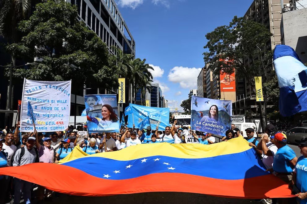 Cientos de personas con banderas y pancartas marchan en una calle de Caracas para demandar elecciones libres y la habilitación de María Corina Machado.